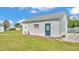 Garage featuring white siding, blue door, concrete pathway, well-maintained lawn, and adjacent gravel area at 619 Somerset Loop, Auburndale, FL 33823