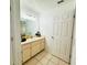 Bright bathroom featuring a vanity with a mirror, cabinets, tile flooring, and a door leading to the hallway at 709 N Polk Ave, Fort Meade, FL 33841