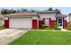 Charming single-story home featuring a two-car garage and vibrant red accents on the exterior and freshly mowed lawn at 7337 Hunters Greene Cir, Lakeland, FL 33810