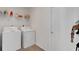 Bright laundry room featuring white washer and dryer with ample shelving for storage and wood-look flooring at 7642 Habersham Dr, Lakeland, FL 33810
