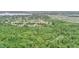 Expansive aerial view of a home nestled amidst lush greenery, with a lake and neighborhood visible in the distance at 848 17Th Ne Ter, Winter Haven, FL 33881