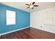 Bedroom with hardwood floors, a light blue accent wall, and natural light streaming through the window at 943 Hamilton Place Ln, Lakeland, FL 33813