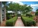 Paver walkway bordered by manicured hedges leads to the home, surrounded by verdant landscaping at 943 Hamilton Place Ln, Lakeland, FL 33813