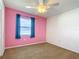 Bedroom with pink walls, carpeted floor, ceiling fan, and a window with blue curtains at 1034 Shadowbrook N Dr, Lakeland, FL 33813