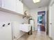 Bright laundry room with a utility sink, white cabinets, and neutral tile flooring at 1034 Shadowbrook N Dr, Lakeland, FL 33813