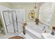 Bright bathroom featuring a corner tub, glass shower, and neutral tiling at 1117 Stonebrooke Ln # 58, Lakeland, FL 33803