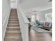 Carpeted staircase leads to a bright and comfortable living room with stylish sofas and a chandelier at 1125 Mattie Pointe Blvd, Auburndale, FL 33823