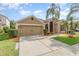 Tan single-story home with a 2-car garage, beautiful landscaping, and a well-maintained lawn at 13852 Eylewood Dr, Winter Garden, FL 34787