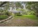 Spacious backyard featuring lush greenery, a screened-in porch, and a charming pathway at 1589 Royal Forest Ct, Lakeland, FL 33811