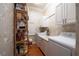 Well-organized laundry room with white cabinets, charming wallpaper, and functional shelving for ample storage at 1589 Royal Forest Ct, Lakeland, FL 33811