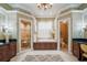 A luxurious main bathroom with a soaking tub, dual vanities, a walk-in shower, and decorative wallpaper at 1589 Royal Forest Ct, Lakeland, FL 33811
