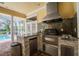 Outdoor kitchen with stainless steel appliances, stone accents, and adjacent pool access, perfect for entertaining at 1589 Royal Forest Ct, Lakeland, FL 33811