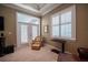 Sitting area in the main bedroom, featuring a comfortable chair, window with plantation shutters, and French doors at 1589 Royal Forest Ct, Lakeland, FL 33811
