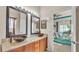 Modern bathroom showcasing dual vessel sinks, wooden cabinetry, and a view into the main bedroom at 1975 Country Manor St, Bartow, FL 33830