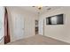A standard bedroom featuring neutral walls and carpet, ceiling fan, mounted TV, and entry doors at 1975 Country Manor St, Bartow, FL 33830