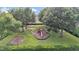 Community playground featuring swings, slides, and climbing structures, surrounded by mature shade trees and landscaping at 1975 Country Manor St, Bartow, FL 33830