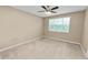 A light-filled bedroom with a ceiling fan, a large window with blinds, and neutral carpeting at 228 Magneta Loop, Auburndale, FL 33823