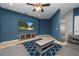 Cozy bonus room with blue walls, a modern ceiling fan, a television and a comfortable seating area on a patterned rug at 228 Magneta Loop, Auburndale, FL 33823
