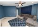 Comfortable living room area with blue walls, ceiling fan, carpeting, a television, and a sectional sofa with a patterned rug at 228 Magneta Loop, Auburndale, FL 33823