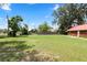 Expansive backyard with lush green lawn, mature trees, and a glimpse of the red-roofed house at 330 Diesel Rd, Mulberry, FL 33860