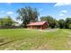 Spacious backyard with a red-roofed house, green lawn, mature trees, and a fence, offering a serene outdoor space at 330 Diesel Rd, Mulberry, FL 33860
