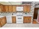Kitchen with wood cabinets, white appliances, tiled floor and a window above the sink at 3315 Cross Fox Dr, Mulberry, FL 33860