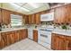 Kitchen with wood cabinets, white appliances, tiled floor and a window above the sink at 3315 Cross Fox Dr, Mulberry, FL 33860