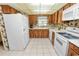 Kitchen with wood cabinets, white appliances, tiled floor and a window above the sink at 3315 Cross Fox Dr, Mulberry, FL 33860