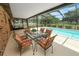 Relaxing screened-in patio with a glass table set, overlooking the sparkling pool and landscaped backyard at 3315 Cross Fox Dr, Mulberry, FL 33860
