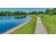 Scenic view of a pond with a paved path and green grass in a park-like setting at 3427 Waterlute Way, Lakeland, FL 33811