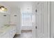 Well-lit bathroom with double vanity, tiled floor, and glass block window above tub at 367 Cloverdale Rd, Winter Haven, FL 33884