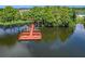 Picturesque lake view features a wooden dock with benches surrounded by lush trees and tranquil water at 3806 Osprey Pointe Cir, Winter Haven, FL 33884