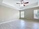 Large primary bedroom featuring a tray ceiling, ceiling fan, and two windows at 3806 Osprey Pointe Cir, Winter Haven, FL 33884