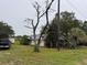 Quaint white brick home featuring mature trees, satellites, and an overgrown front yard at 4011 E Robinson Dr, Haines City, FL 33844