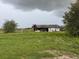 Weathered, neglected outbuilding in a rural setting with overgrown foliage and a storm brewing at 4011 E Robinson Dr, Haines City, FL 33844