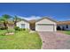 Beautiful one-story home with lush green lawn, palm trees, and brick driveway leading to a two-car garage at 4188 Muirfield Loop, Lake Wales, FL 33859