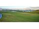 Scenic golf course view featuring lush green grass, rolling hills, and a tranquil lake backdrop at 4188 Muirfield Loop, Lake Wales, FL 33859