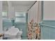 Classic bathroom with stylish blue tile, a sink, toilet, and a shower with a vibrant curtain at 4219 Forest Hills Dr, Lakeland, FL 33813
