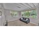Bright living room featuring multiple windows, carpeted floor, and modern gray sofa at 4219 Forest Hills Dr, Lakeland, FL 33813