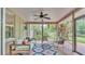 A screened-in porch with ceiling fan, comfortable seating, and views of the lush backyard at 4219 Forest Hills Dr, Lakeland, FL 33813