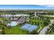 Community aerial showcasing pool, tennis courts, playground, and lake views under a bright blue sky at 6261 Great Bear Dr, Lakeland, FL 33805