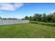 Expansive backyard featuring green grass, a pristine white fence, and lush trees at 6261 Great Bear Dr, Lakeland, FL 33805
