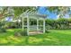Landscaped backyard with a cozy pergola swing surrounded by green grass and mature trees providing shade at 633 Hart Lake Dr, Winter Haven, FL 33884