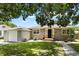 Charming single-story home with neutral siding, green lawn and complemented by mature trees overhead at 819 Glendale St, Lakeland, FL 33803