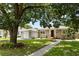 Charming single-story home with neutral siding, green lawn and complemented by mature trees overhead at 819 Glendale St, Lakeland, FL 33803