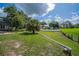 View of the backyard, with a privacy fence, mature trees, grassy lawn and some palm trees at 929 Hammock Shade Dr, Lakeland, FL 33809