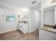 Well-lit bathroom featuring a granite countertop, white cabinetry, and wood-look flooring at 967 Hunters Meadow Ln, Lakeland, FL 33809