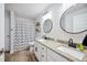 Modern bathroom with dual vanities, granite countertops, a shower-tub combo, and wood-look floors at 967 Hunters Meadow Ln, Lakeland, FL 33809