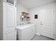 Organized laundry room with washer, dryer, storage, and stylish wallpaper accent at 967 Hunters Meadow Ln, Lakeland, FL 33809