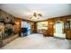 Inviting living room featuring a stone fireplace, wood paneling, and seamless flow to the kitchen at 10 Webb Rd, Winter Haven, FL 33881